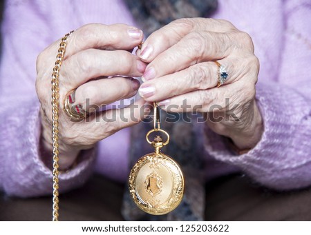 Time goes by/ Old woman hands holding between her fingers a gold pocket watch/ Barcelona. Spain. November 2010