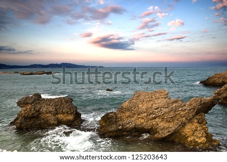 After sunset moments, in a Costa Brava\'s beach, with the cloudy rose sky, and two bigs rocks in the foreground/ Twilight in the coast/. L\'Escala. Costa Brava. Setember 2012. Catalonia. Spain.