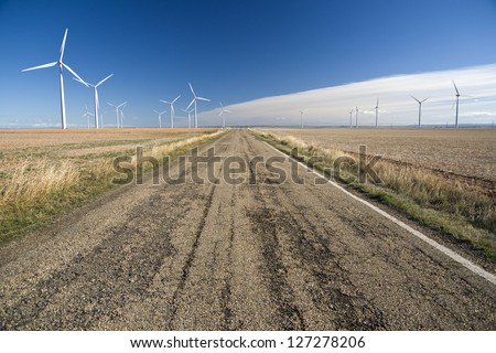 A rural road between windmills landscape/ Sustainable Development/