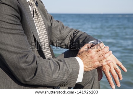 Bussiness man in a suit checking his watch by the sea / Break time