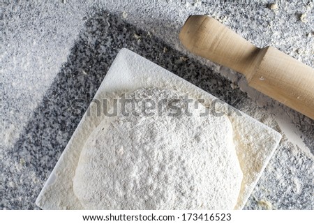 A food composition with pizza dough ready to cook with a wooden kneader / Raw dough pizza