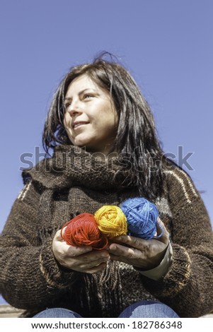 Young knitter with coloured yarns of wool in her hands / Young knitter with coloured yarn of wool