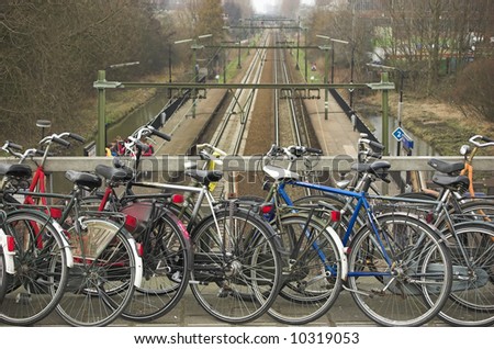 City bicycles parked on a viaduct above a train railway