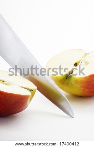 Long bladed kitchen knife cutting through a red apple