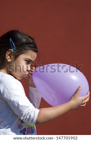 Mixed race girl blowing up balloon
