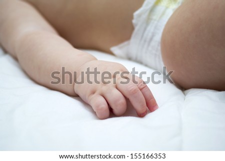 Baby sleeping in the crib with the focus on her tiny hand