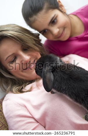 Mother and daughter playing with pet rabbit at home