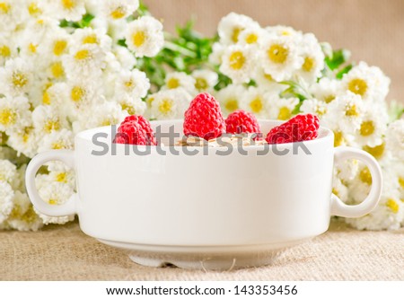 Oatmeal with raspberries in the bowl and flowers