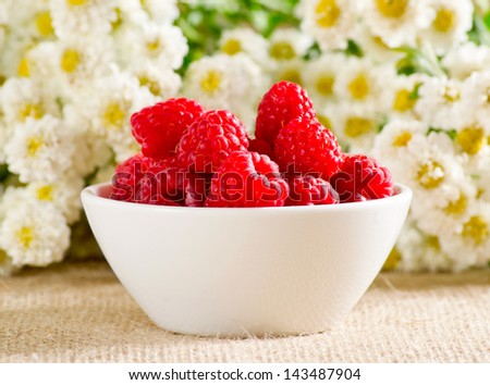 Raspberries in the bowl and flowers
