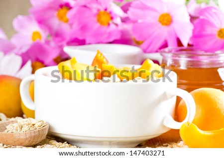 Apricot  in the bowl, oatmeal, honey,  milk jug and flowers
