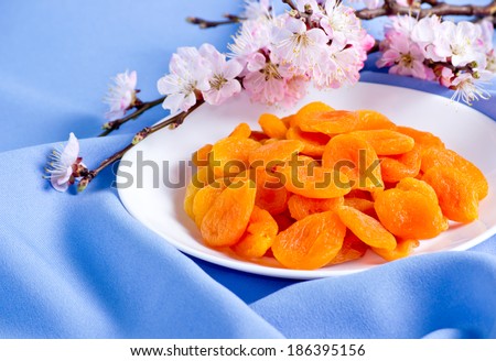 Dried apricots with almonds and blossoming branch on blue  fabric
