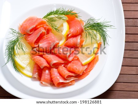 Sliced salted salmon served with lemon on the wooden board