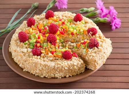 Cake with nuts, candied fruits and raspberries on  bamboo mat and cloves