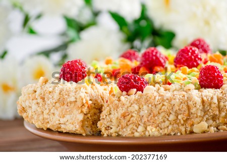 Cake with nuts, candied fruits and raspberries on  bamboo mat and flowers