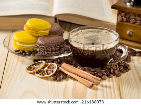 Coffee cup with macaroon, cinnamon, dried lemony and culinary book on the wooden table