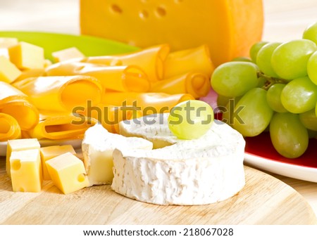 Round camembert cheese with smoked cheese and grapes on the wooden board