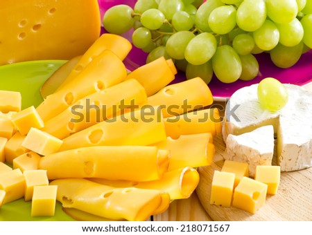 Round camembert cheese with smoked cheese and grapes on the wooden board