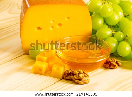 Smoked cheese, honey, walnuts and grapes on the wooden table
