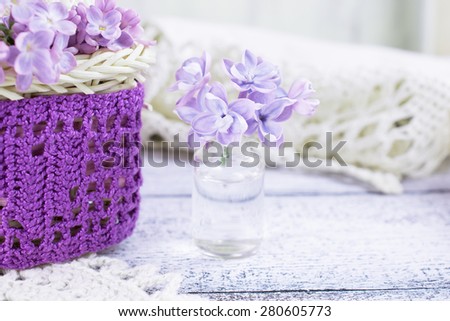 Lilac flowers in a small glass bottle and ornamental openwork knitted cloth. For this photo applied color toning and blurring effect.