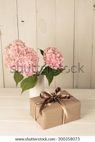 Hortense in vase and gift box on wooden board in shabby chic style