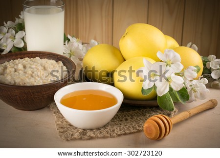 Yellow apples with oatmeal, milk and honey, twig of apple tree on the background of wooden wall. For this photo applied vignetting effect.