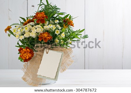 Tagetes flower bouquet with decorative greeting card on white wooden boards in shabby chic style