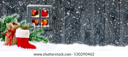 Santa's boot and bag with gifts and cones on wooden wall background and glowing lights outside the window