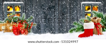 Christmas banner. Santa boot, balls, bag with gifts and cones on wooden wall background and glowing lights outside the window.