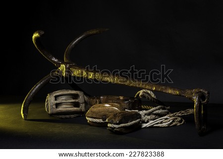 Ancient marine tools: Pulleys ropes, Anchor with black background and yellow grazing light