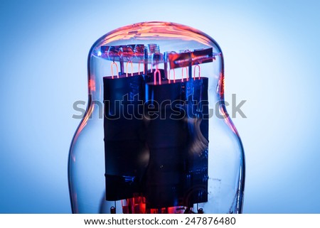 Close up picture of filaments of electronic vacuum tube rectifier. Blue and white background