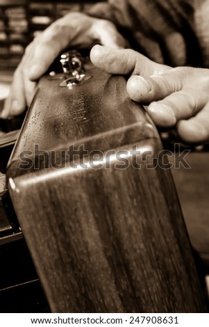 Hands of a joiner that touches a wood artefact. Sepia colour