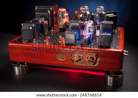 Hi end amplifier, with wood chassis and many electronic vacuum tubes : triode, rectifier, stabilizer, in a dark background