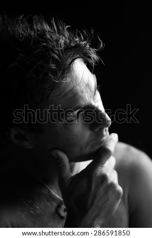 Low key black and white portrait of cute man. Thinking expression