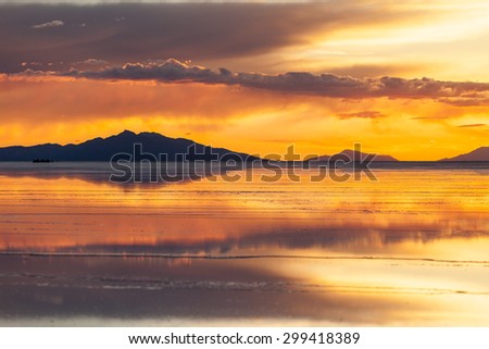 Sunset in salar de Uyuni. Reflection of the clouds in the wet surface of salt. Mountain and clouds background