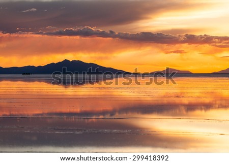 Sunset in salar de Uyuni. Reflection of the clouds in the wet surface of salt. Mountain and clouds background