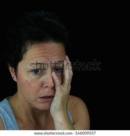 Woman holding face in emotional upset. Mental health/stress/depression. Isolated on black background.