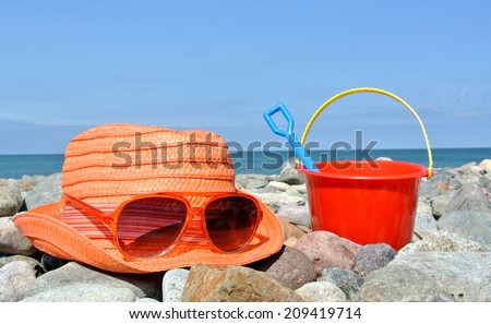 sun hat, sunglasses and bucket with spade on British pebble beach