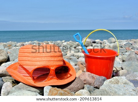 Parent and child at the beach. Adult\'s hat, sunglasses and child\'s bucket with spade to symbolize parent and child on holiday together.