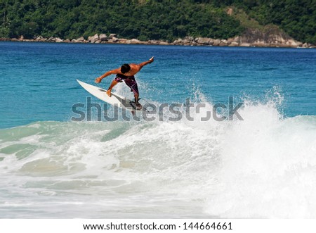 Young guy surfing the wave in a sunny day