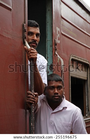 NUWARA ELYA, SRI LANKA - SEPTEMBER 28, 2014: Two young man stand up at the train door during a slow train  trip