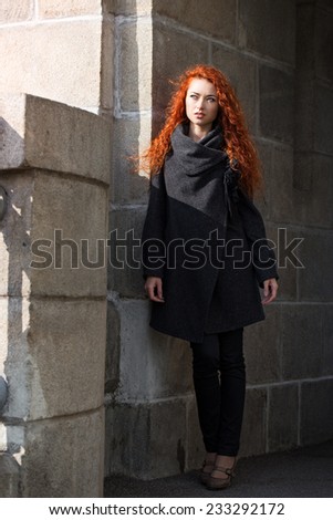 Beautiful blond young woman dressed in a coat walking down the street of the old town center