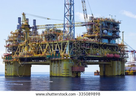 South China Sea, Malaysia - June 4: Supply vessel and oil rig platform on calm blue sea. South China Sea, Malaysia, June 4th, 2015