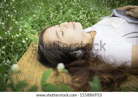 Woman relaxing in garden with book and music
