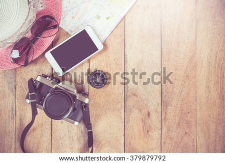 Preparation for travel,trip vacation, tourism mock up of cell phone,road map,compass,camera,hat on wooden table.