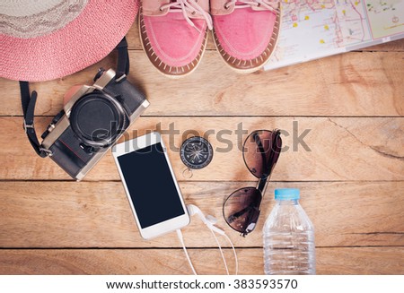 Preparation for travel,trip vacation, tourism mock up of cell phone,road map,compass,camera,hat,shoes on wooden table.