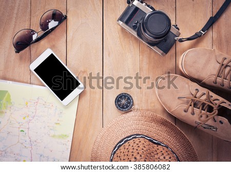 Preparation for travel,trip vacation, tourism mock up of cell phone,road map,compass,camera,hat,leather shoe,sunglasses on wooden table.