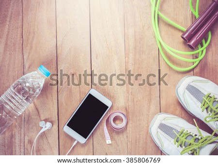 fitness concept with Exercise Equipment ,jump rope,shoes,smartphone,Measure A,on wooden table.