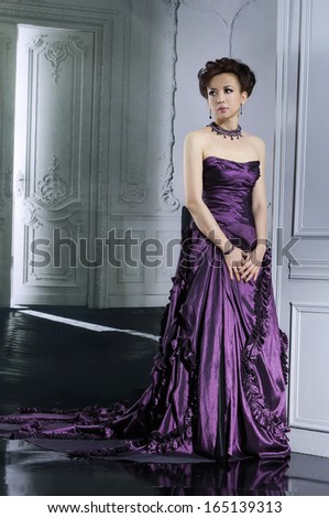 beautiful woman wearing purple luxurious wedding dress in full-length standing posing