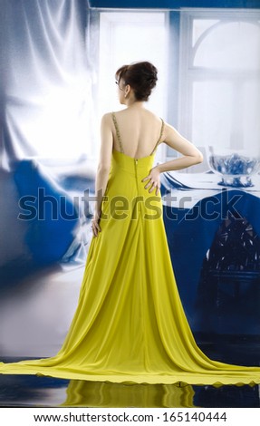 full-length beautiful woman wearing yellow wedding dress back posing