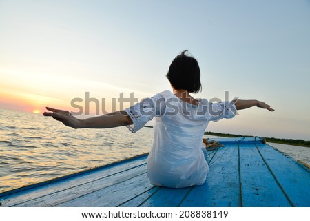 healthy middle aged woman traveling by wood boat at sunset